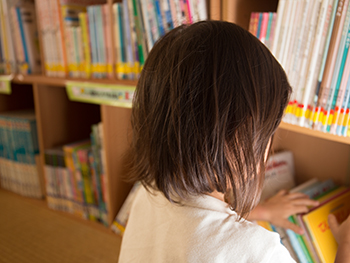 図書館で一人絵本を探す女の子の後ろ姿